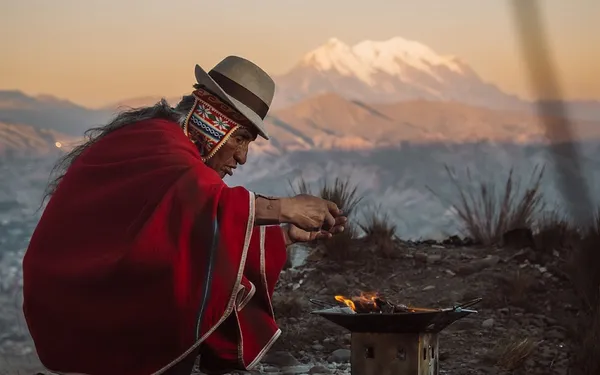 A man in a red poncho above La Paz, the Illimani behind