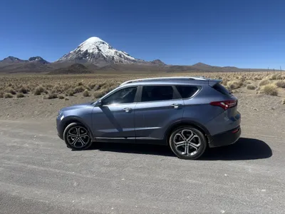 Side view of the Jetour SUV on a dirt road in the altiplano, Sajama behind