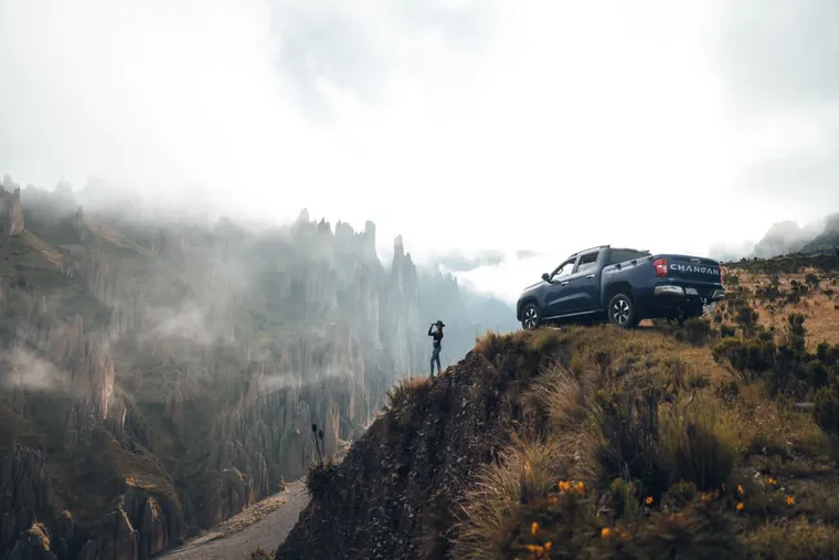 A Fat Cat vehicle parked at the edge of the valley in the mist, a traveler taking photos