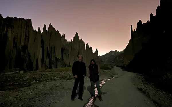 Two travelers walking into the valley before sunrise