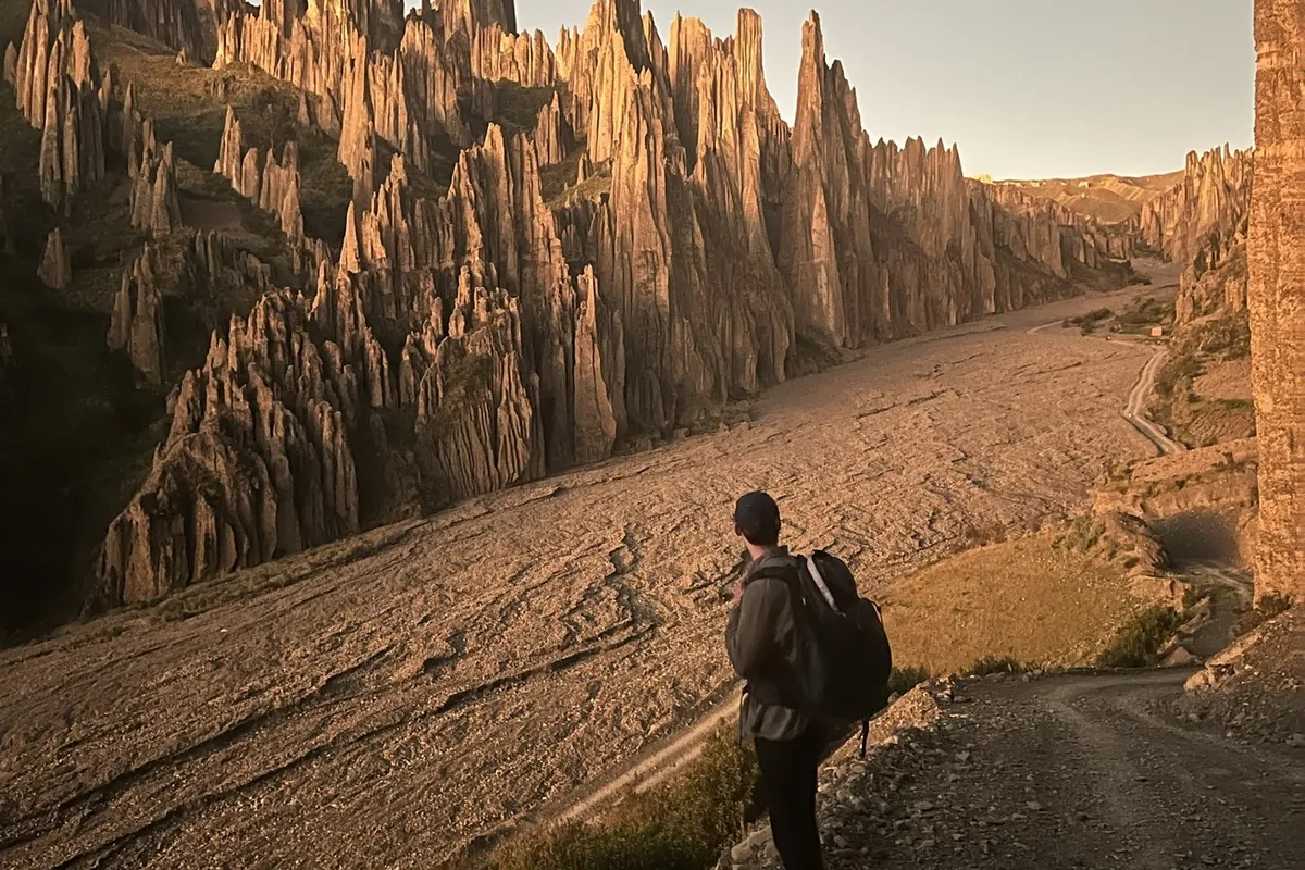 Golden hour in Valle de las Ánimas: a hiker among the spires lit orange by the setting sun