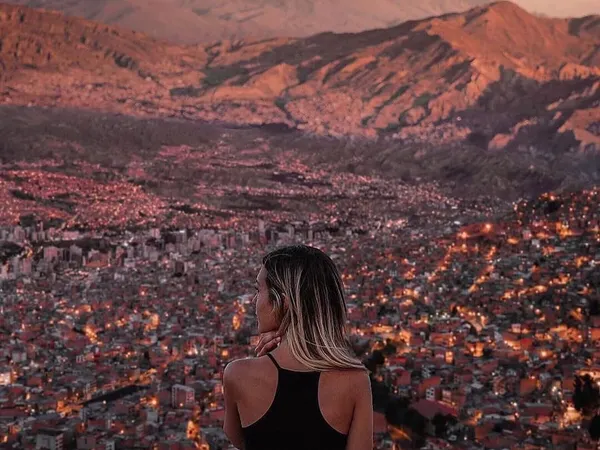 Killi Killi viewpoint at dusk: the city of La Paz lit up below and the Illimani behind