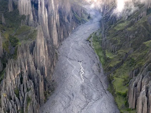 Valle de las Ánimas from above: stone spires on both sides of the dry riverbed, clouds drifting between the peaks