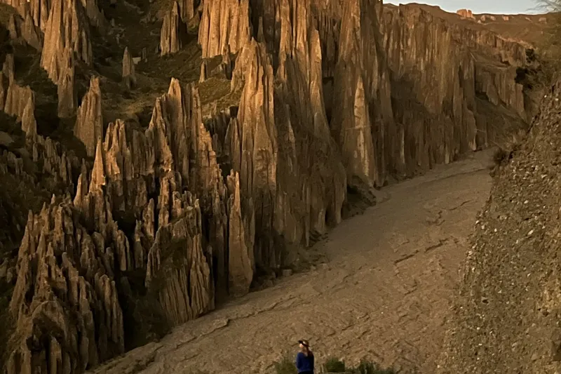 A hiker on the loose, dusty trail between the spires